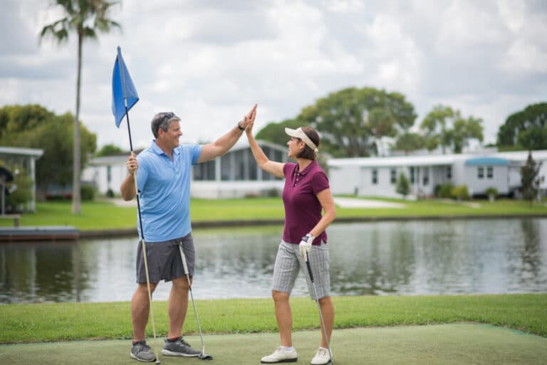 A couple high fiving each other while playing in a golf course